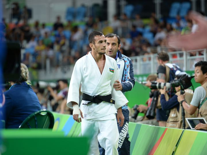 Two judoka in blue and white uniforms gripping during an Olympic contest in Rio