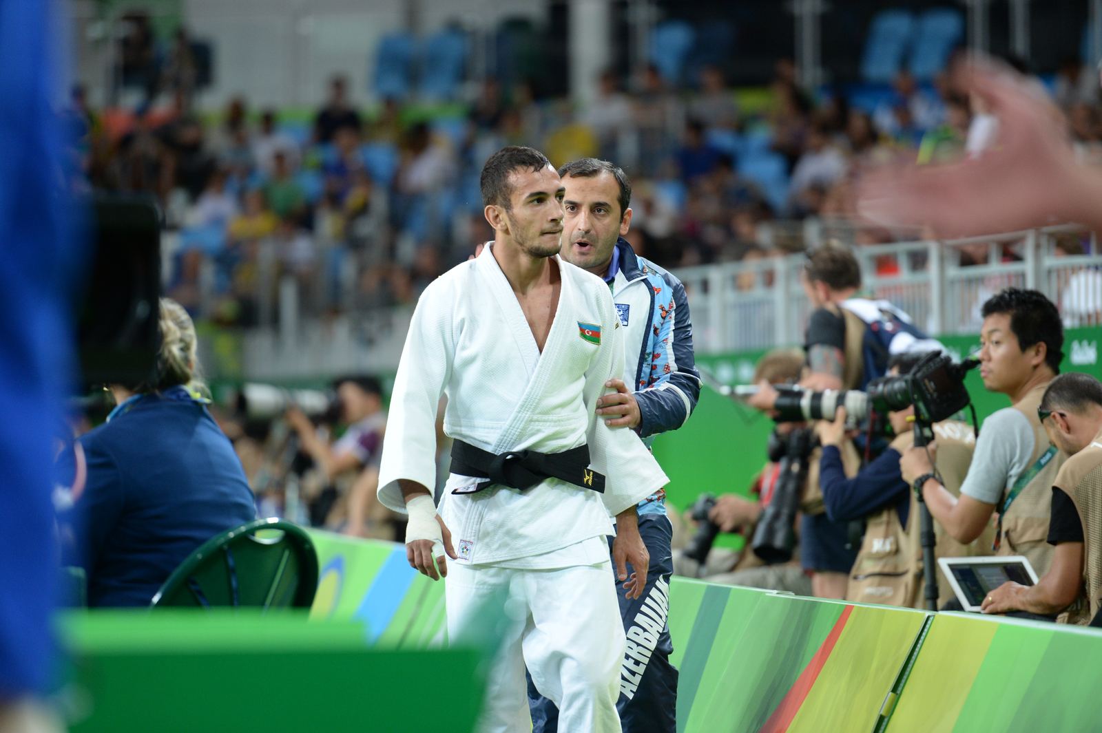 Two judoka in blue and white uniforms gripping during an Olympic contest in Rio