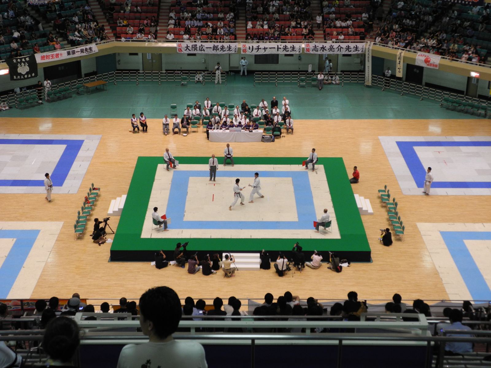 Two karate athletes in white uniforms face each other in a tournament final