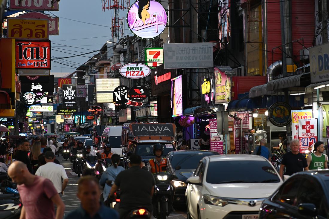 A busy, brightly lit city street at dusk with many people